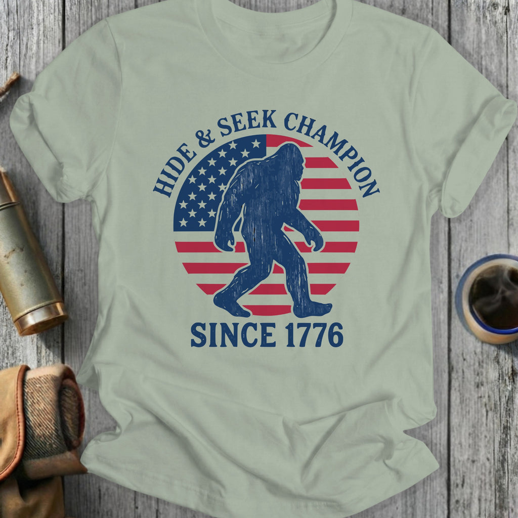 Bigfoot silhouette against US flag, "Hide & Seek Champion Since 1776" text.