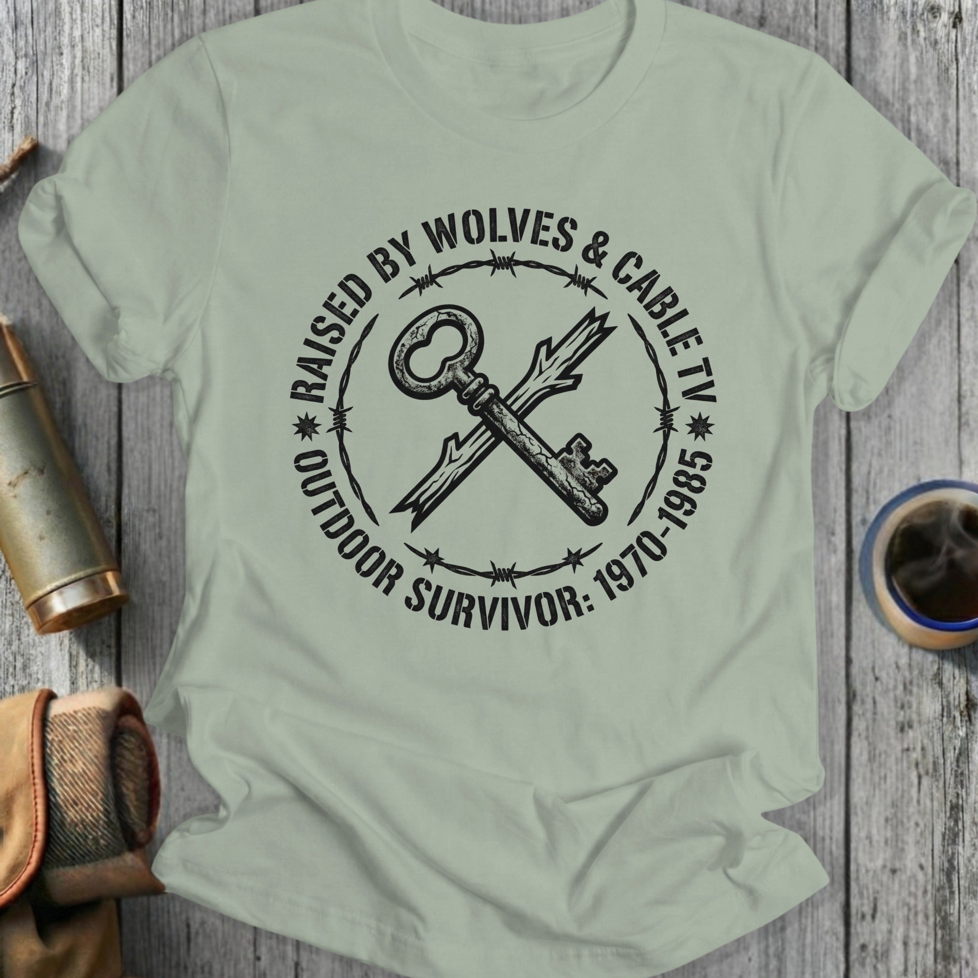 T-shirt with "Raised by Wolves & Cable TV Outdoor Survivor" text and crossed key graphic.