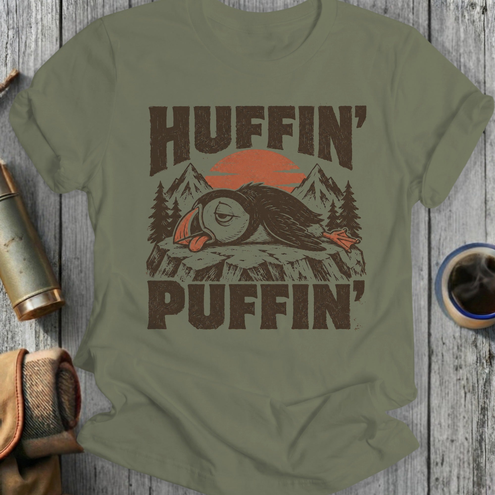 Puffin wearing a crown with "Huffin' Puffin'" text, sunset and mountains background.