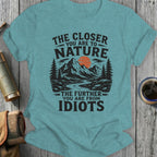 Teal t-shirt with text: "THE CLOSER YOU ARE TO NATURE THE FURTHER YOU ARE FROM IDIOTS" and a mountain scene.