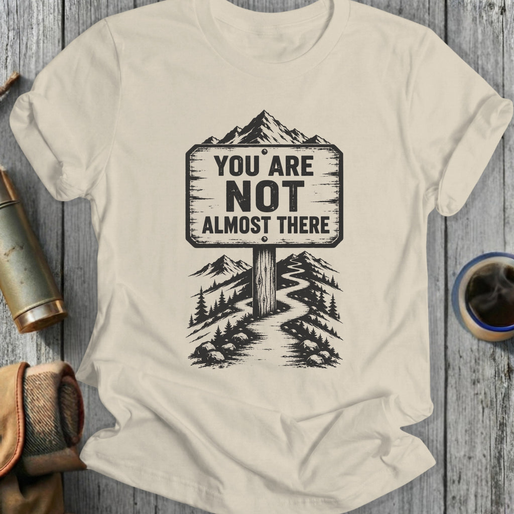 T-shirt with a sign reading "You are not almost there" on a mountain path.