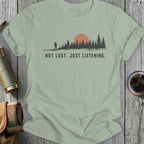 T-shirt with "NOT LOST. JUST LISTENING." text over a forest silhouette and sun.