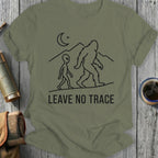 Olive green t-shirt with Bigfoot and alien walking under a moon, text "LEAVE NO TRACE".
