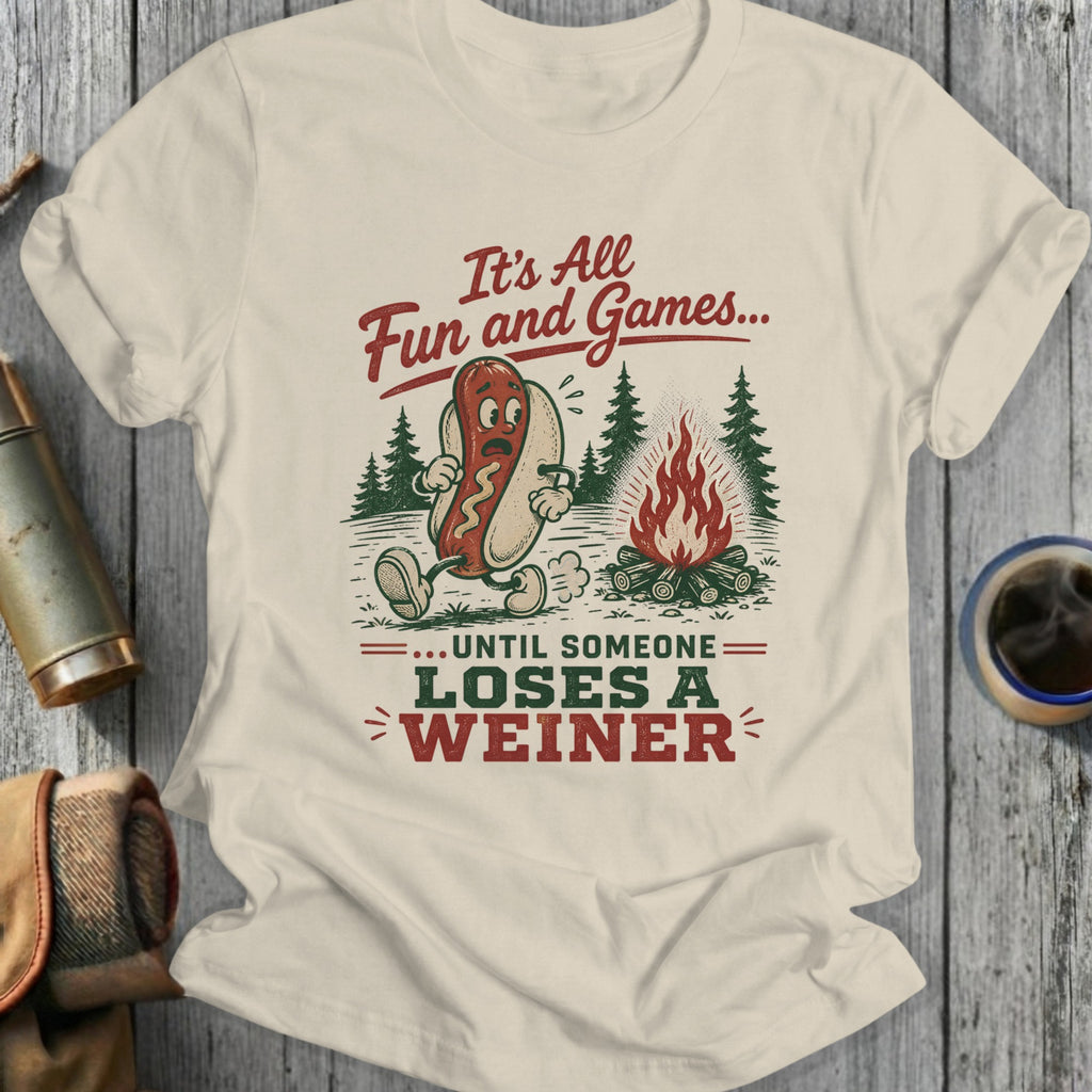 T-shirt with a hot dog around a campfire, reading "It's All Fun and Games... Until Someone Loses A Weiner."