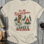 T-shirt with a hot dog around a campfire, reading "It's All Fun and Games... Until Someone Loses A Weiner."