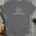Grey t-shirt with a white outline of a raccoon and the text "a little trashy".