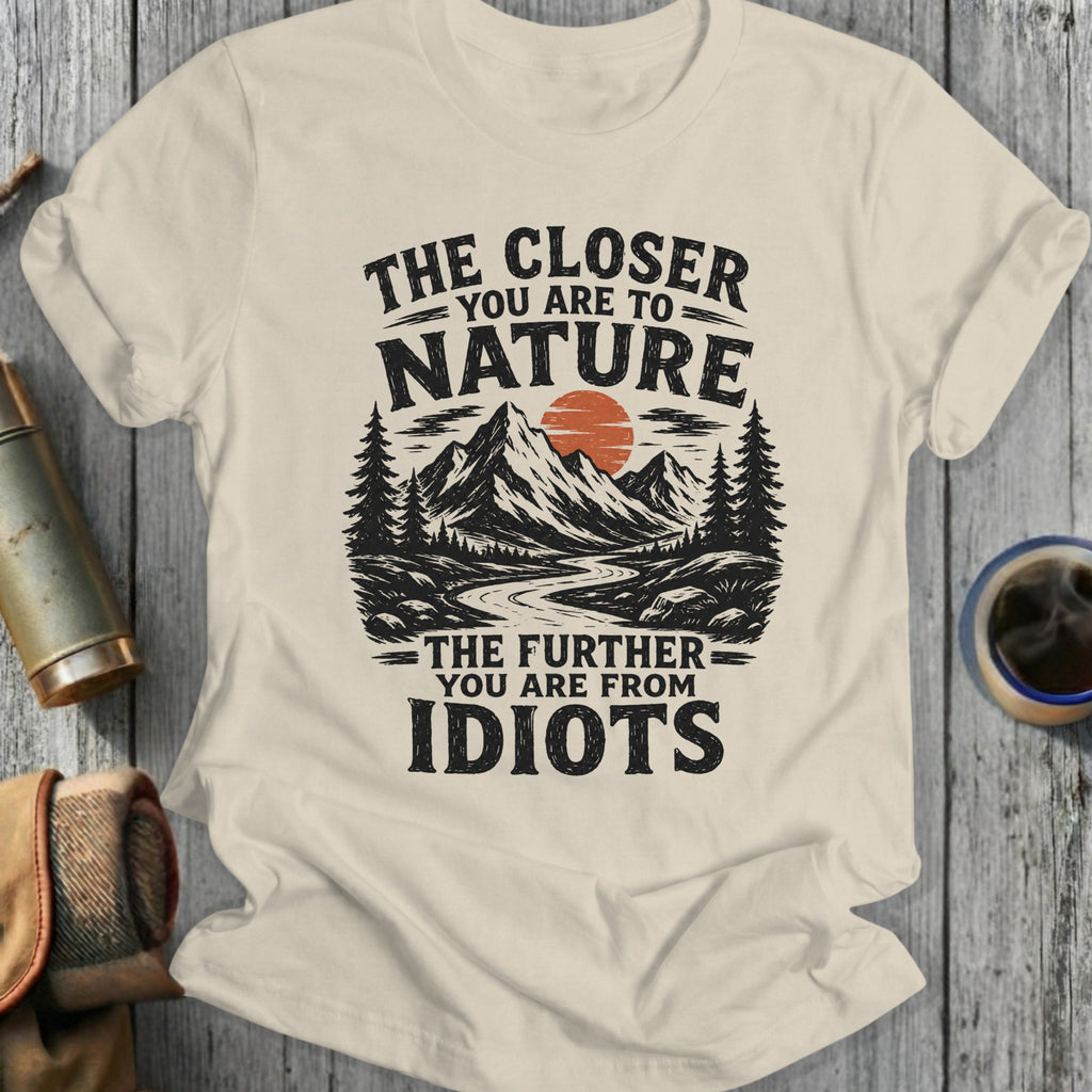 Cream t-shirt with "The Closer You Are To Nature The Further You Are From Idiots" text and mountain graphic.