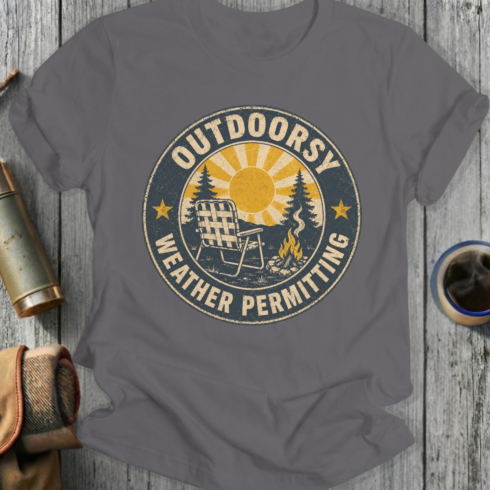T-shirt with distressed circular graphic "Outdoorsy Weather Permitting" and camping scene.