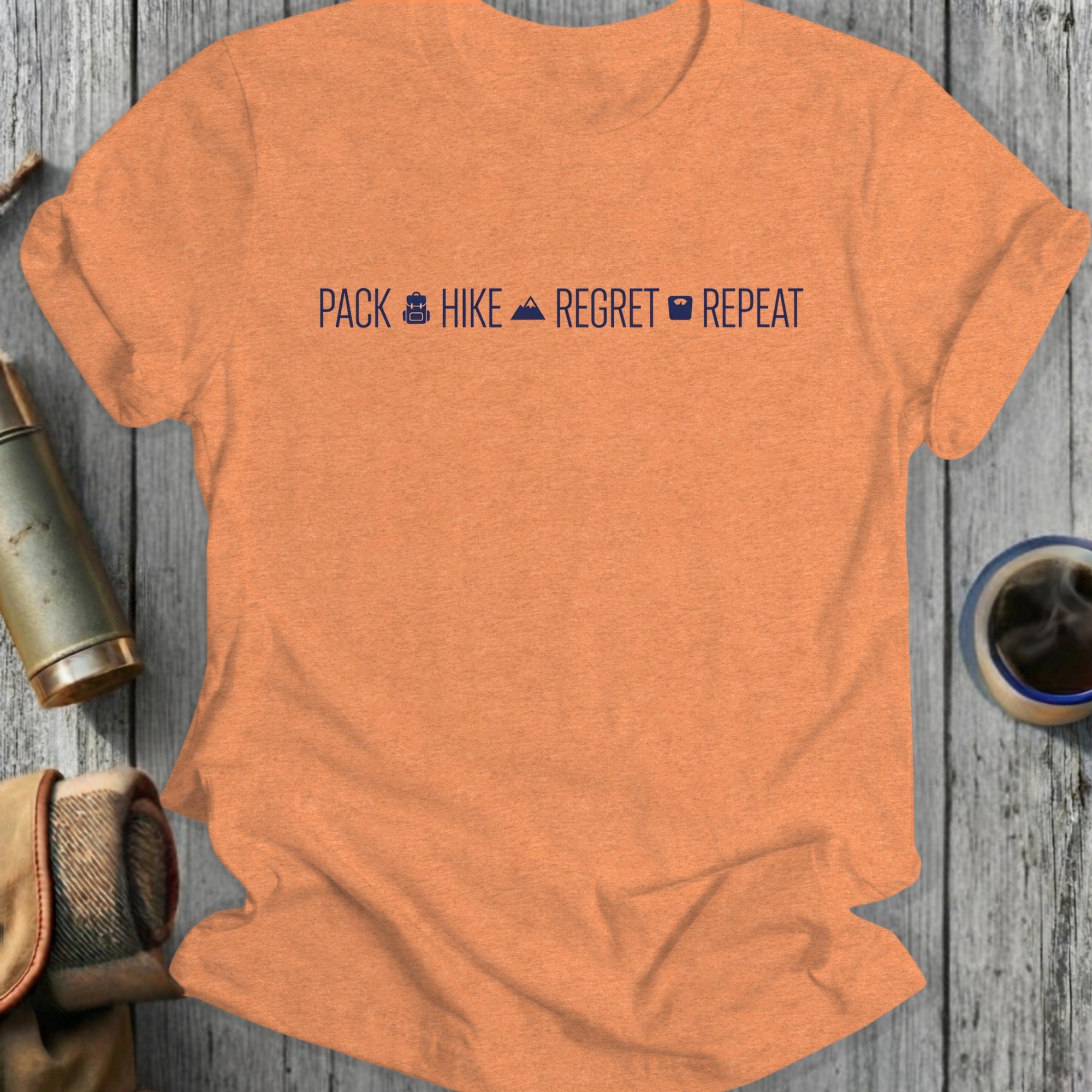 Orange t-shirt with "Pack Hike Regret Repeat" text and icons.