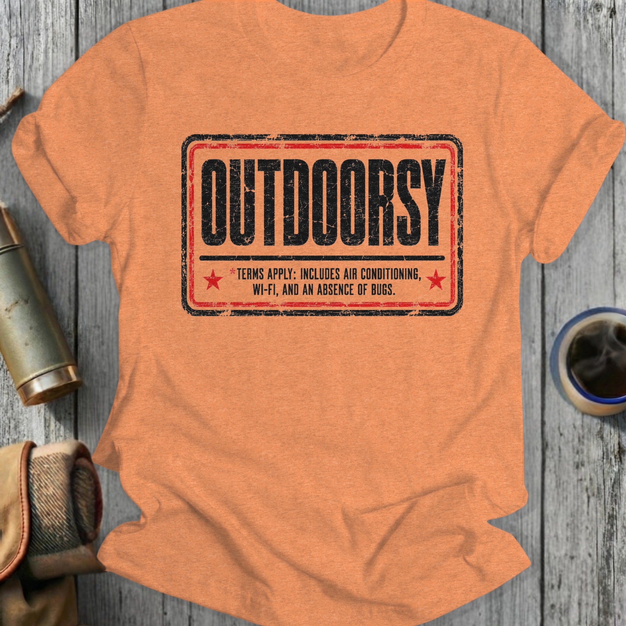 Orange t-shirt with "Outdoorsy" and humorous terms in a distressed stamp graphic.