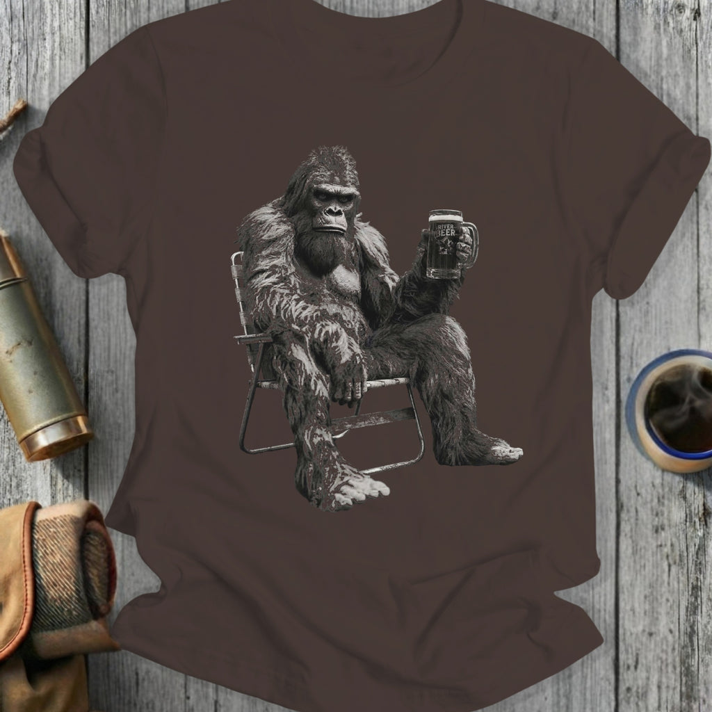 Bigfoot sitting in a chair, holding a mug of beer.