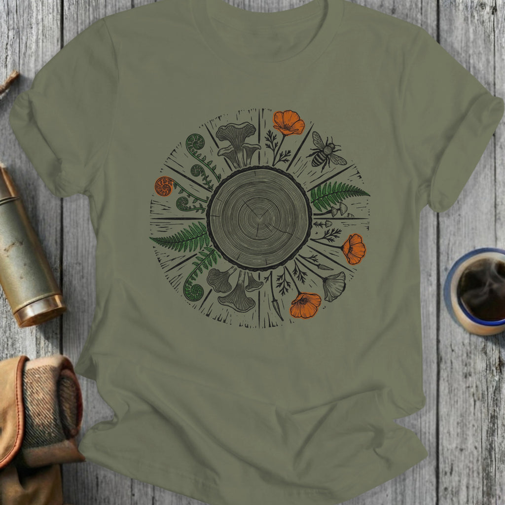 Olive green t-shirt with circular botanical design featuring mushrooms, ferns, and flowers.
