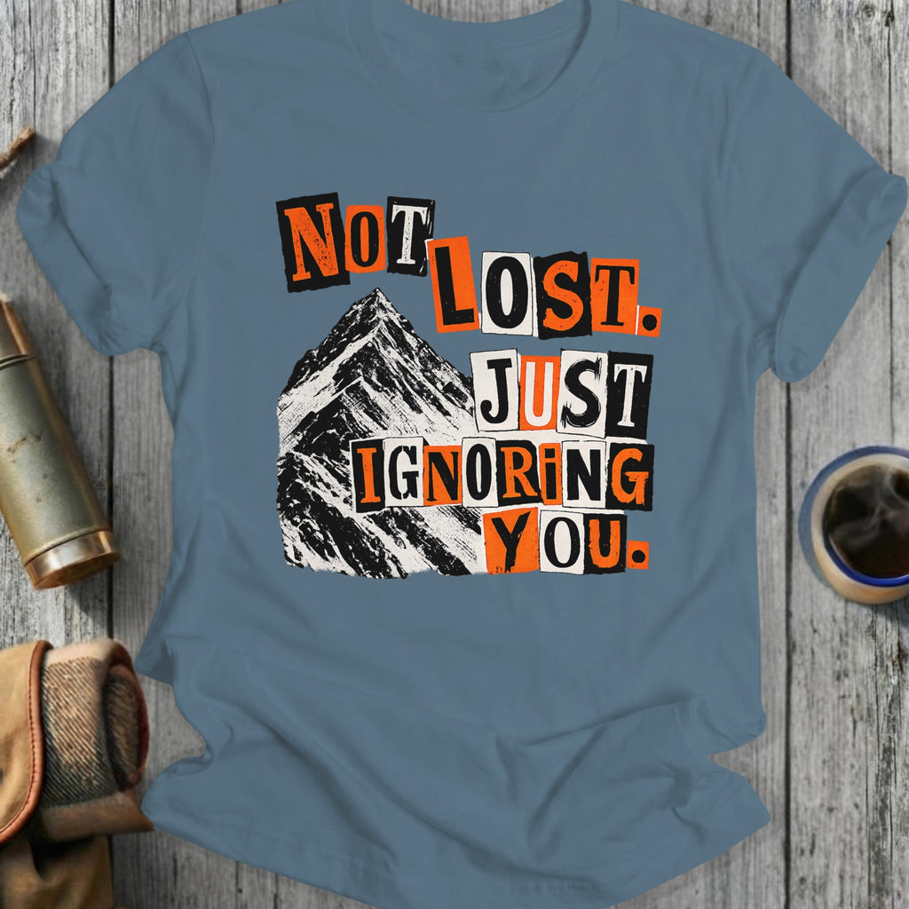 T-shirt with black, orange, and white text "NOT LOST. JUST IGNORING YOU." over a mountain.