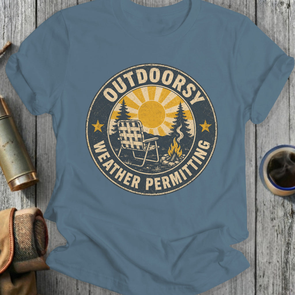 Shirt displaying "OUTDOORSY WEATHER PERMITTING" graphic with sun, chair, campfire, and trees.