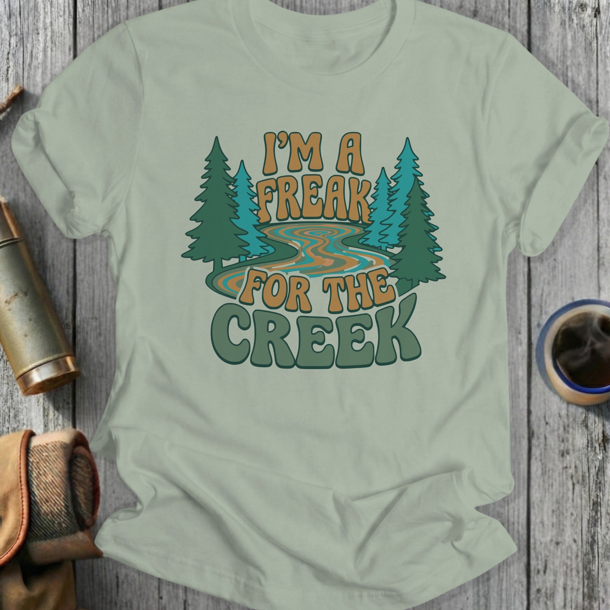 Green t-shirt with "I'M A FREAK FOR THE CREEK" text and trees.