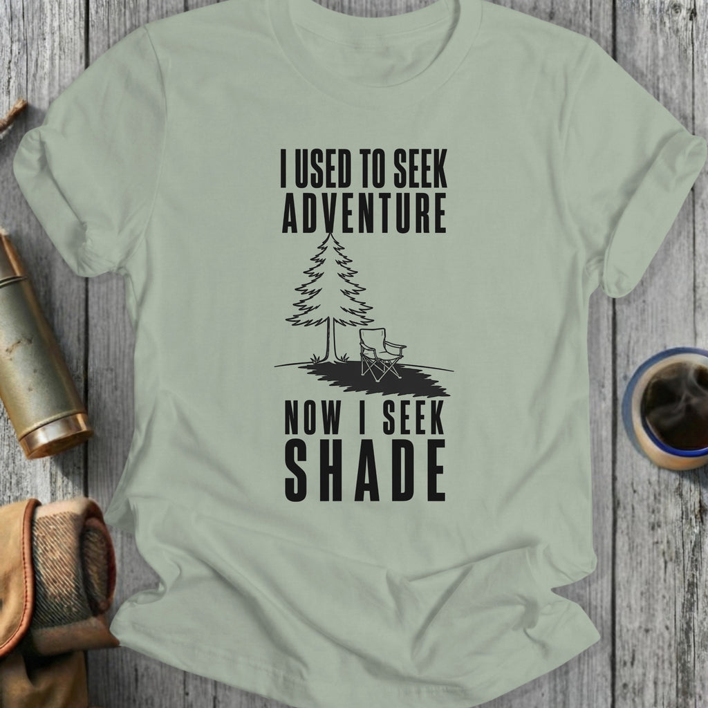 Light green t-shirt with black text "I USED TO SEEK ADVENTURE NOW I SEEK SHADE" and a graphic.