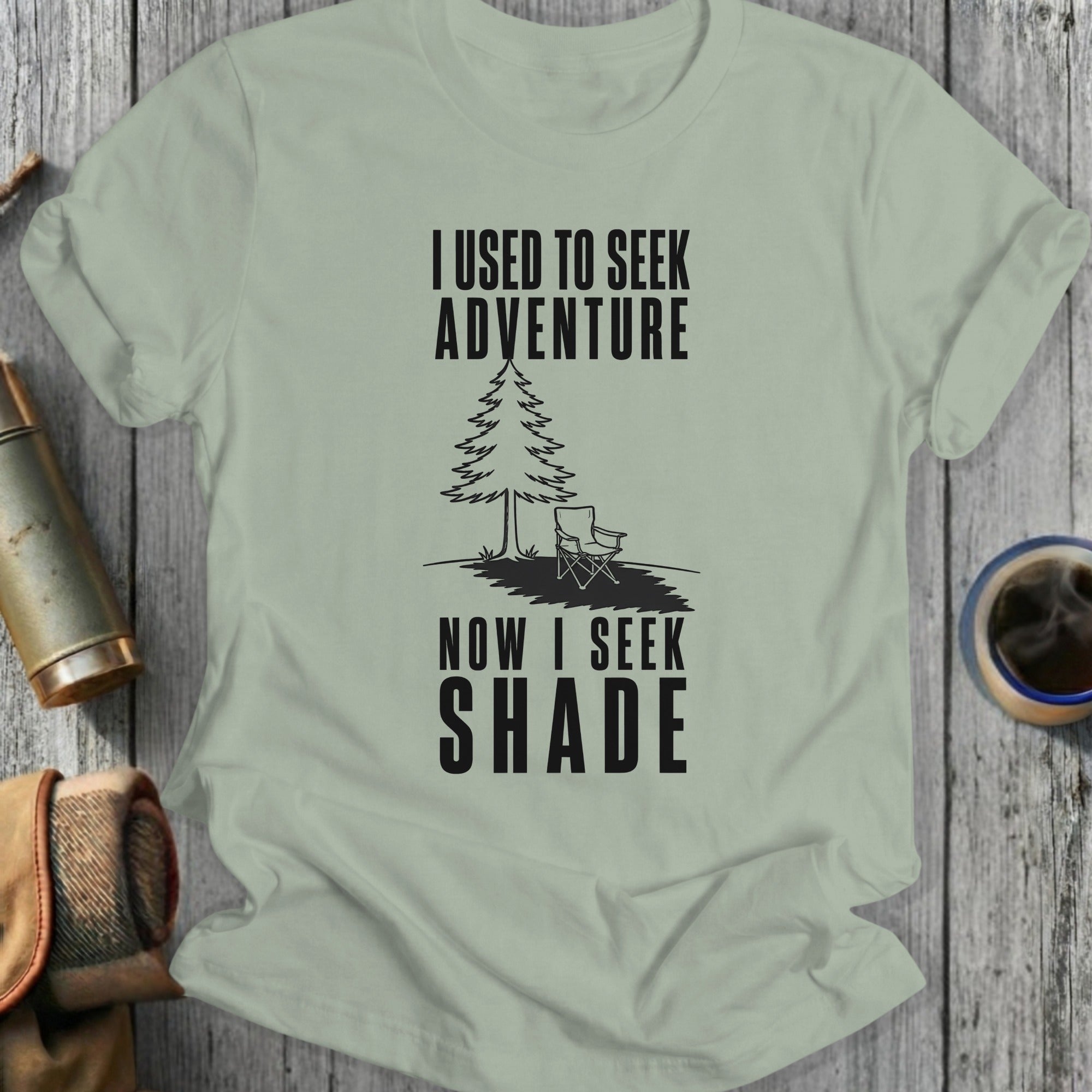 Light green t-shirt with black text "I USED TO SEEK ADVENTURE NOW I SEEK SHADE" and a graphic.
