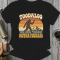 Bigfoot giving peace sign with sunset and mountains, text "TOODALOO MUTHA FUCKAE'S".