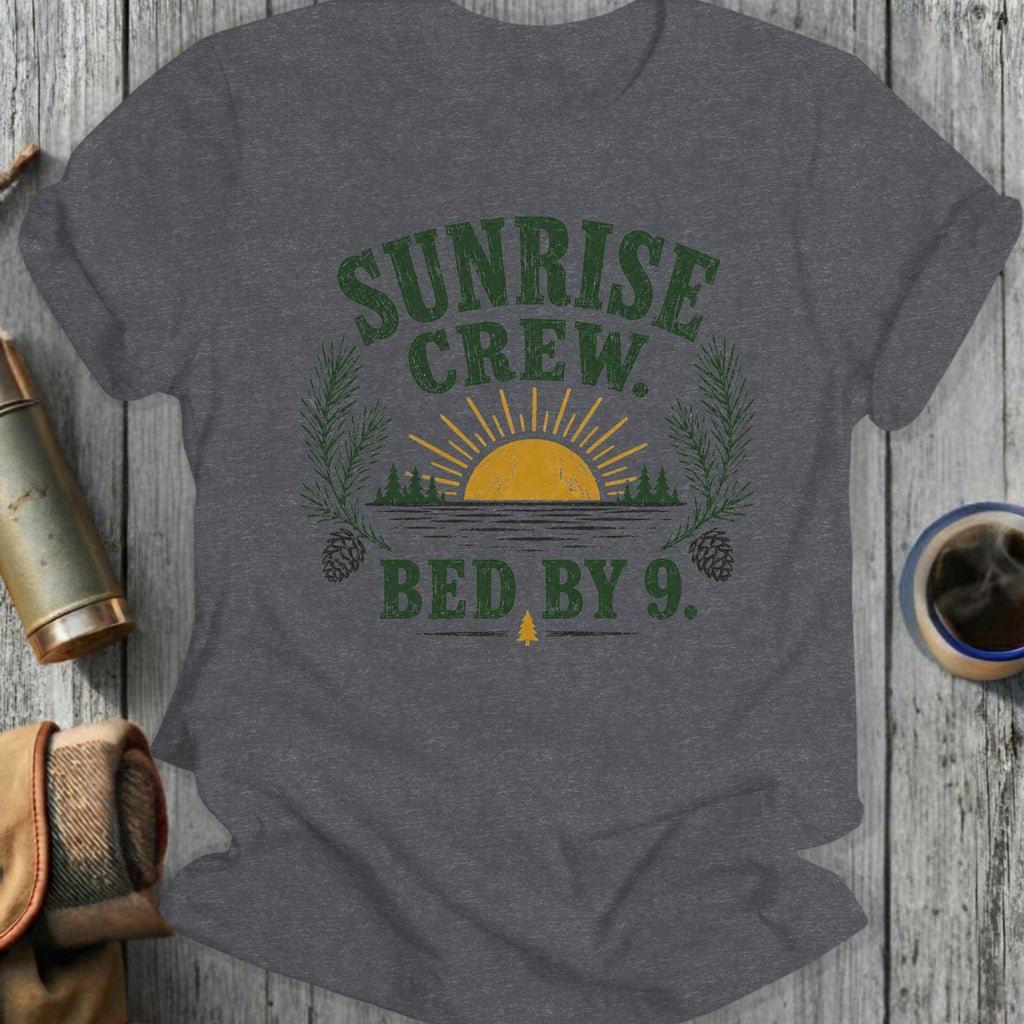 Dark grey t-shirt with "Sunrise Crew. Bed by 9." text and nature graphic.