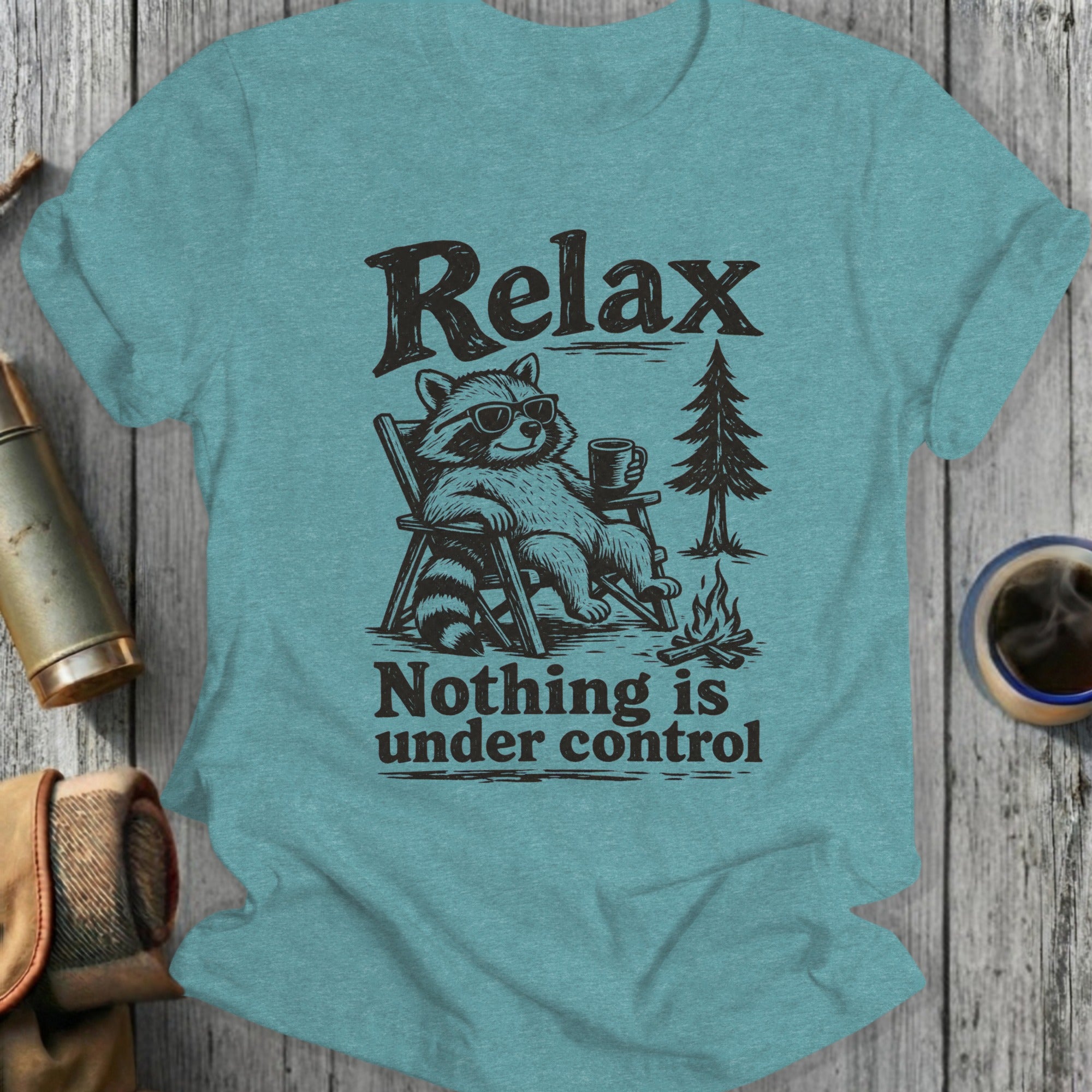 T-shirt with raccoon in chair, campfire, tree, and text "Relax Nothing is under control."
