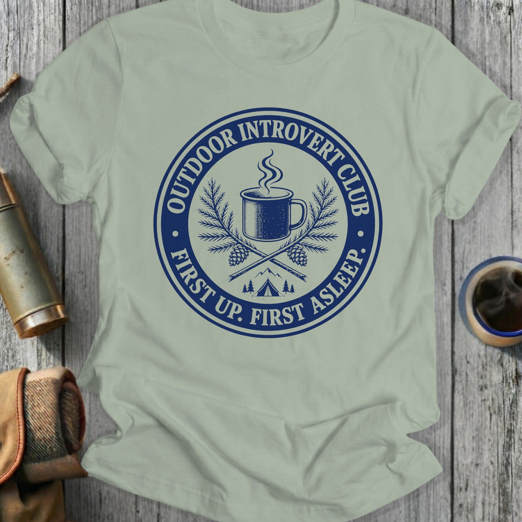 Light grey t-shirt with blue 'Outdoor Introvert Club' graphic of camping mug, pine branches, and tent.