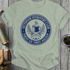Light grey t-shirt with blue 'Outdoor Introvert Club' graphic of camping mug, pine branches, and tent.