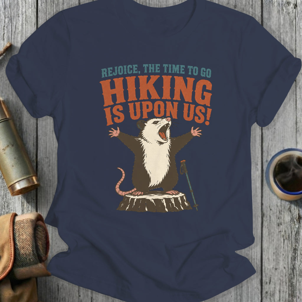 Opossum with arms outstretched and hiking pole, with text "Hiking is upon us!".