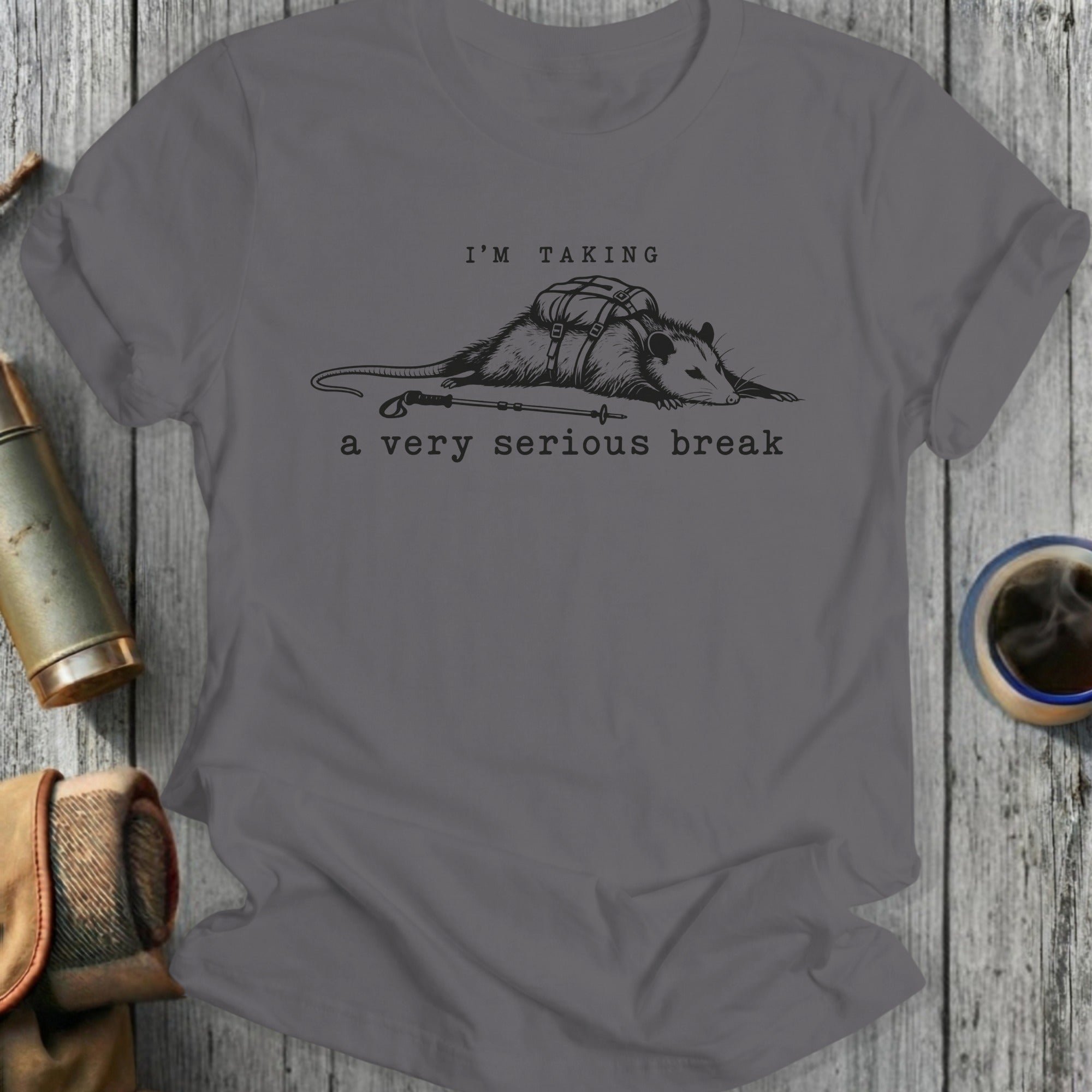 Gray t-shirt with opossum wearing a backpack and trekking pole, text reads "I'M TAKING a very serious break".