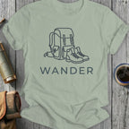 Light gray t-shirt with a minimalist line drawing of a backpack and boots, and the word "WANDER".