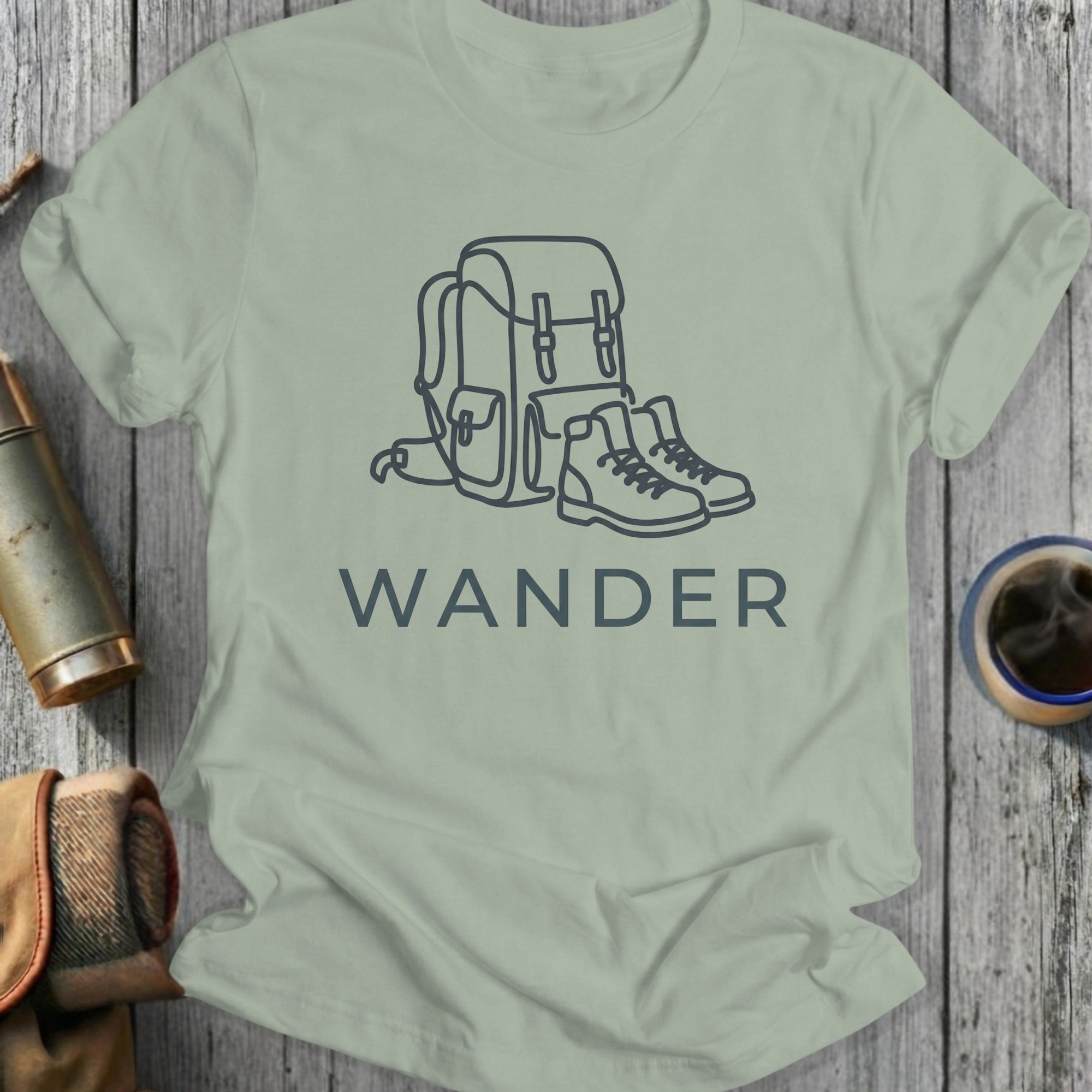 Light gray t-shirt with a minimalist line drawing of a backpack and boots, and the word "WANDER".