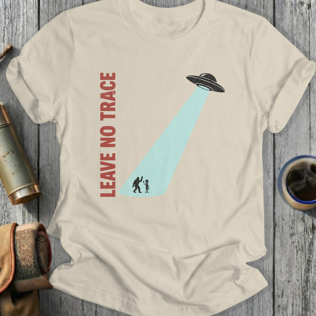 Cream t-shirt with "LEAVE NO TRACE" and Bigfoot being abducted by a UFO.