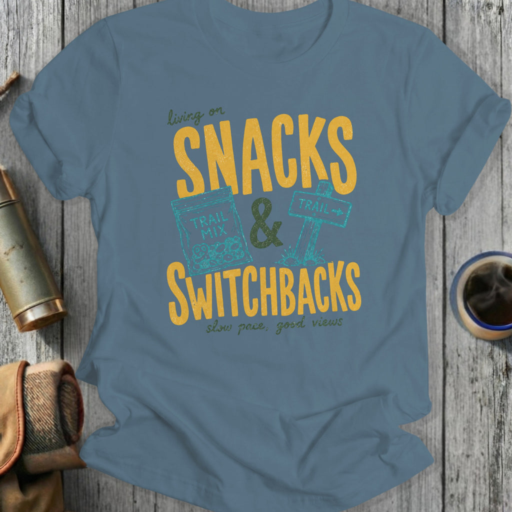 Blue t-shirt graphic with "living on SNACKS & SWITCHBACKS, slow pace, good views".