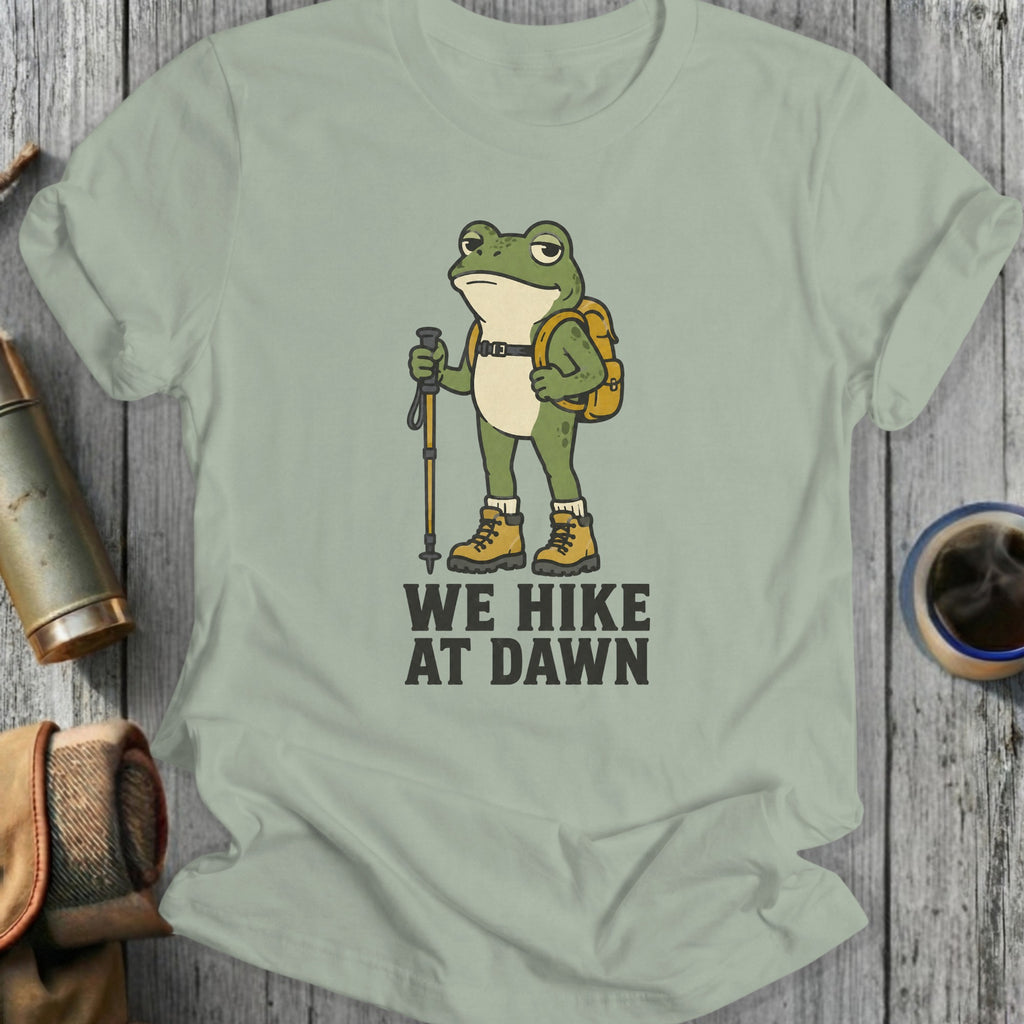 Cartoon frog with backpack and hiking pole, text "WE HIKE AT DAWN".