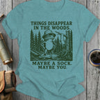 T-shirt with a frog in a hat and text "THINGS DISAPPEAR IN THE WOODS. MAYBE A SOCK. MAYBE YOU."