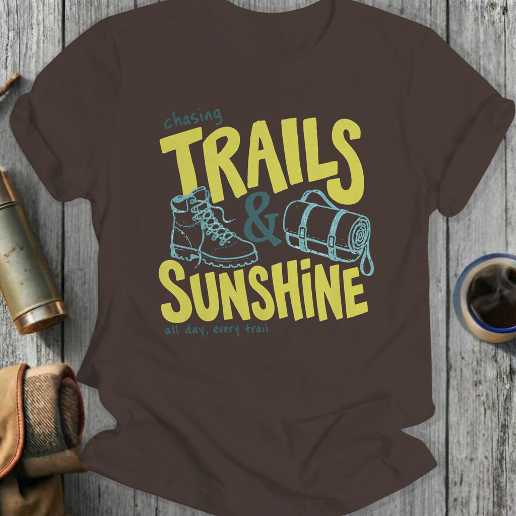 Brown t-shirt with "Chasing Trails & Sunshine" text, boot, and rolled sleeping bag graphic.