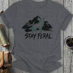 Dark grey t-shirt with green wolf and mountain graphic and "STAY FER AL" text.