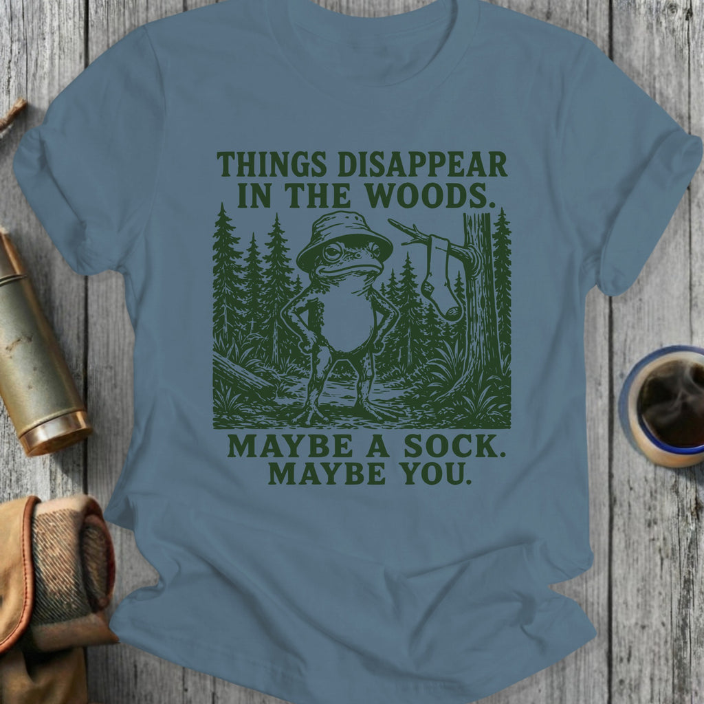Frog in bucket hat in woods, "THINGS DISAPPEAR IN THE WOODS. MAYBE A SOCK. MAYBE YOU."