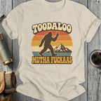 Bigfoot silhouette with peace sign and mountains, text "TOODALOO MUTHA FUCKAAS".