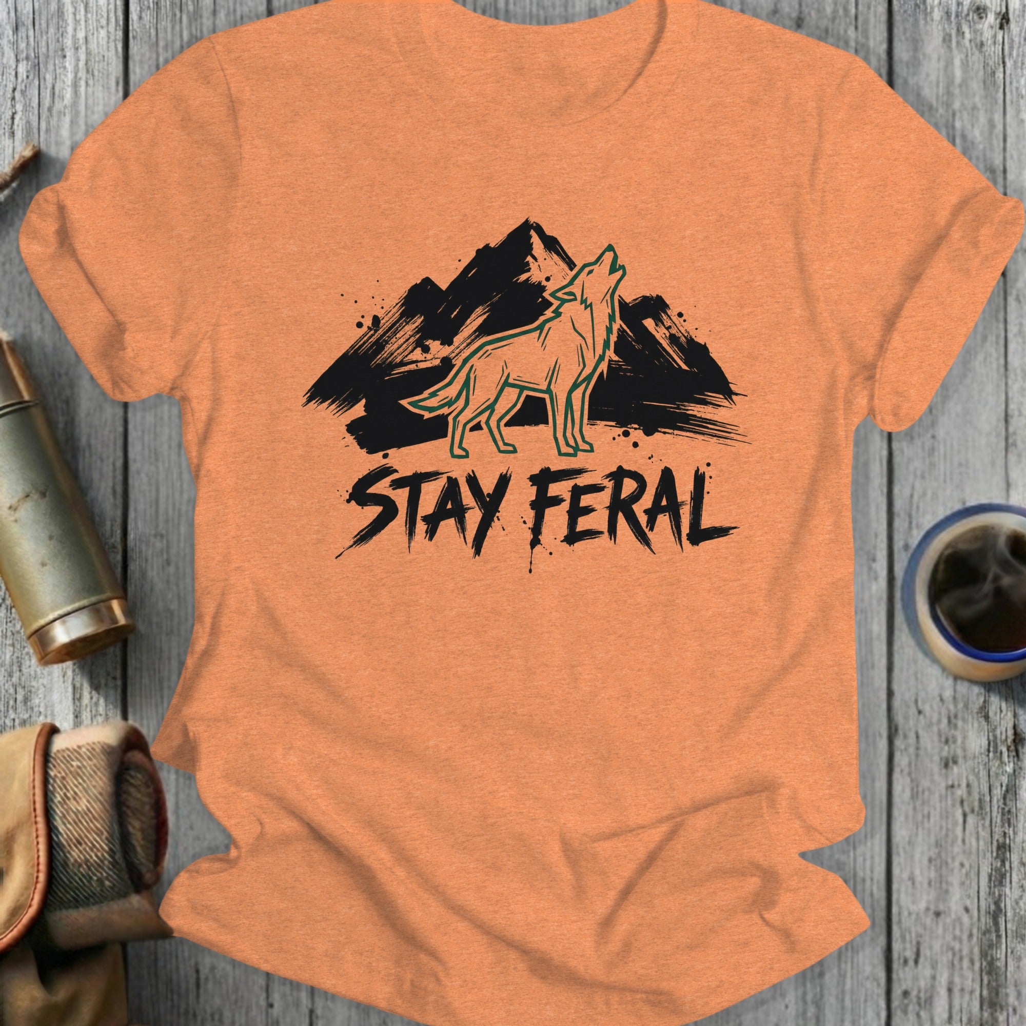 Orange t-shirt with black "STAY FERAL" text and howling wolf over mountains.