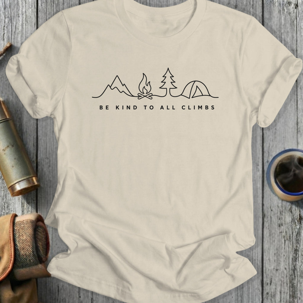 T-shirt with minimalist mountain, campfire, tree, and tent illustration and "Be Kind to All Climbs" text.