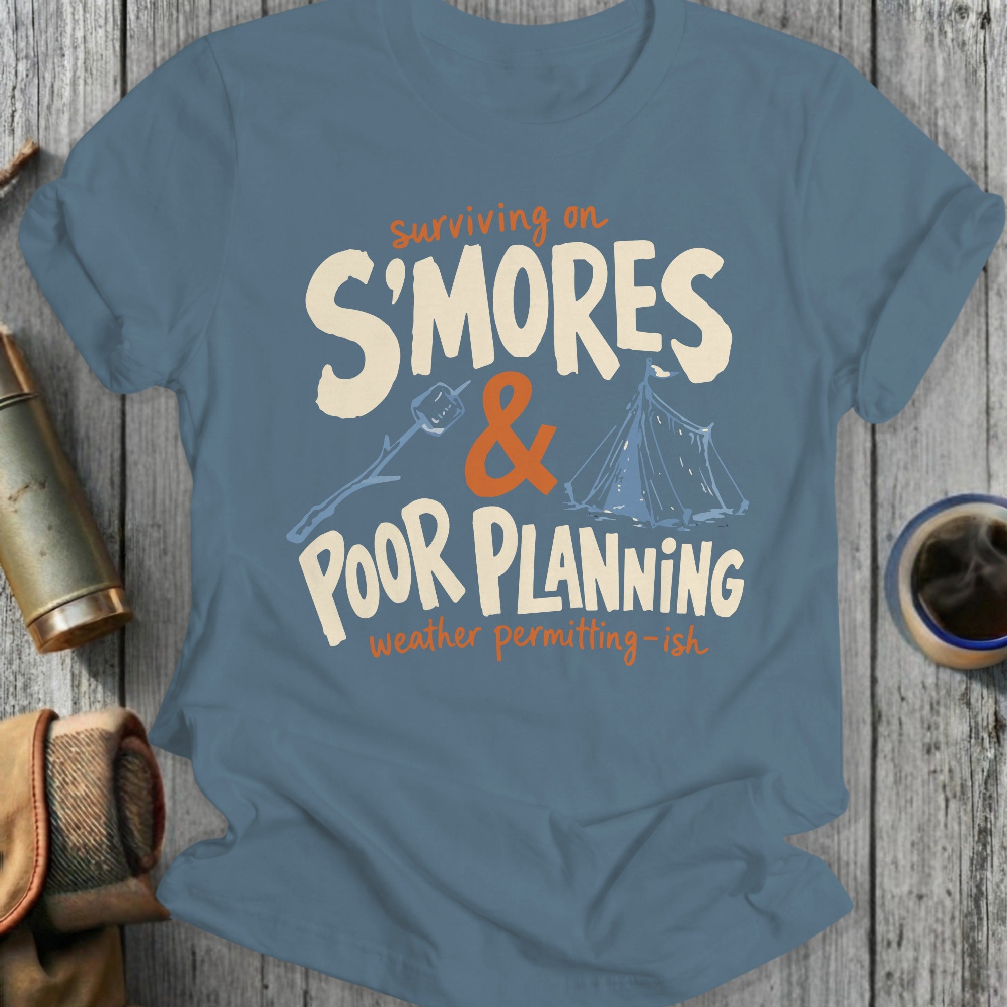 Blue t-shirt with "Surviving on S'mores & Poor Planning" text and camping graphics.