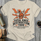 Beige t-shirt with 'Total Knee Destruction Tour' graphic design on a wooden surface.