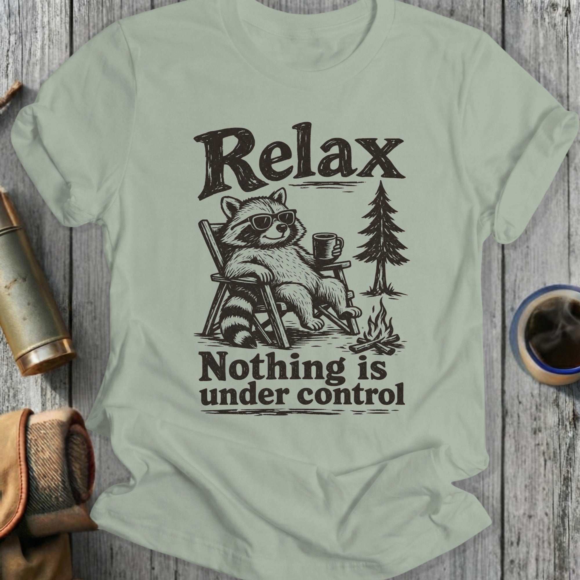 T-shirt with graphic of a raccoon in sunglasses relaxing with a drink, featuring text "Relax" and "Nothing is under control."
