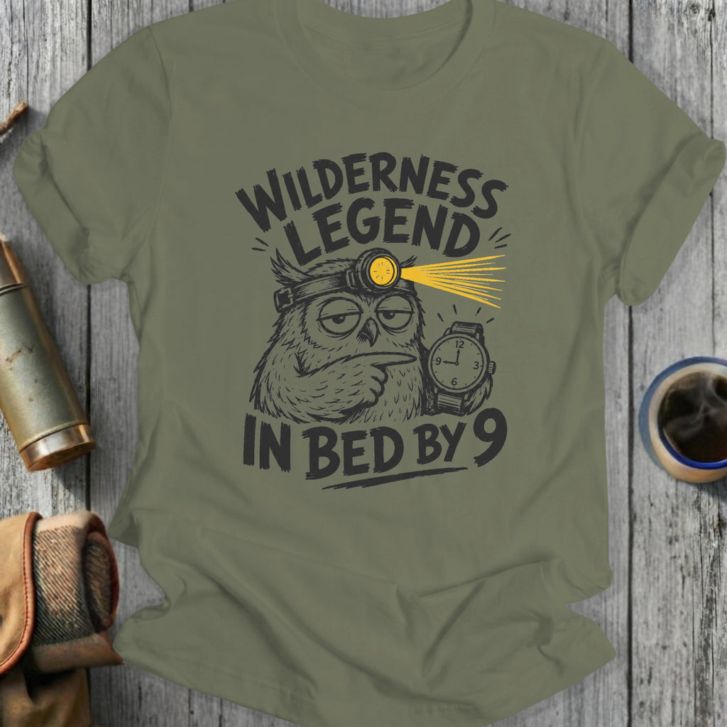 Green t-shirt with cartoon owl wearing headlamp and holding watch, text "Wilderness Legend In Bed By 9".