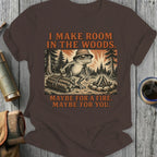 Frog wearing hat in woods, holding logs, with text "I MAKE ROOM IN THE WOODS. MAYBE FOR A FIRE. MAYBE FOR YOU."