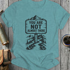 T-shirt with a sign reading "YOU ARE NOT ALMOST THERE" on a mountain path.