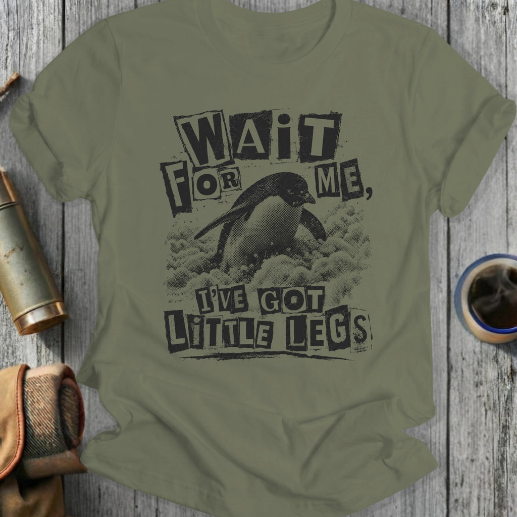 Olive green t-shirt with distressed graphic of a penguin and text "WAIT FOR ME, I'VE GOT LITTLE LEGS".