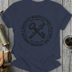 Dark blue t-shirt with crossed keys, barbed wire, and "Raised by Wolves & Cable TV Outdoor Survivor" text.