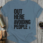 Blue t-shirt with black text "OUT HERE AVOIDING PEOPLE" and a small pine tree.