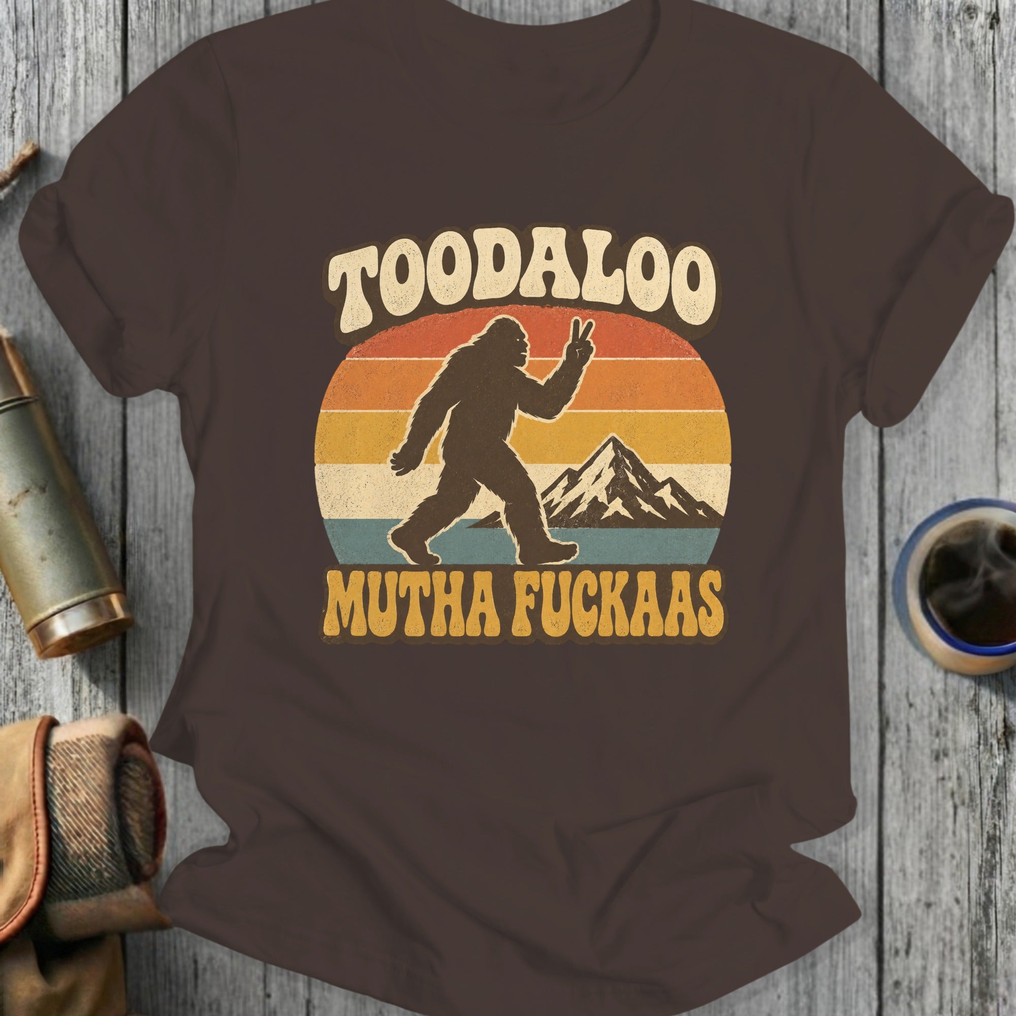 Bigfoot silhouette with peace sign and mountains. "TOODALOO MUTHA FUCKAAS" text.